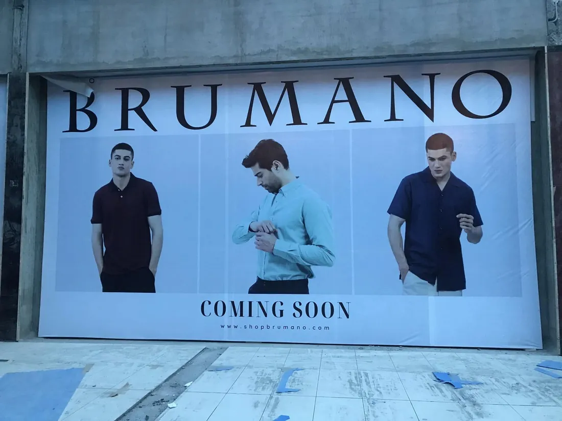 Brumano coming-soon hoarding with three models across a shopfront